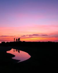 Silhouette of people on beach at sunset