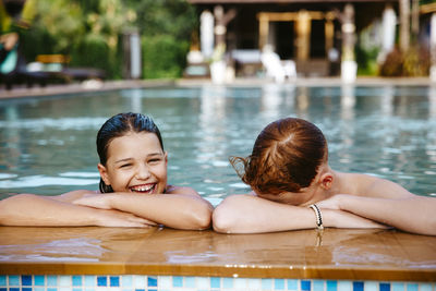 Happy girl with brother enjoying in swimming pool during vacation