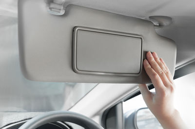 Cropped hand of woman holding sun visor in car