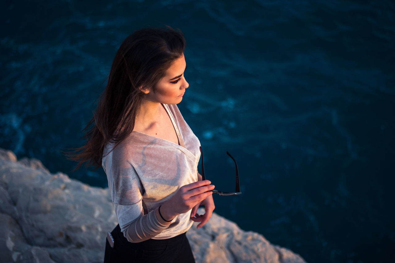 standing, one person, real people, young adult, lifestyles, leisure activity, water, young women, holding, three quarter length, women, casual clothing, focus on foreground, nature, hairstyle, long hair, hair, beautiful woman