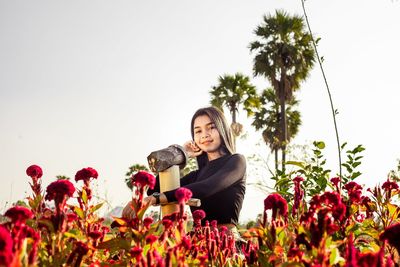 Portrait of smiling young woman against plants against sky