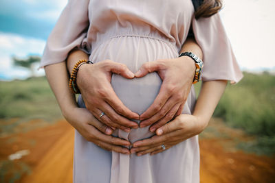 Midsection of woman touching heart shape