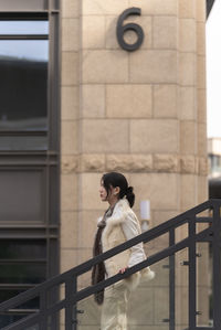 Portrait of woman standing against building