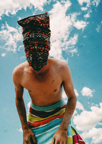 Portrait of shirtless man standing against sky