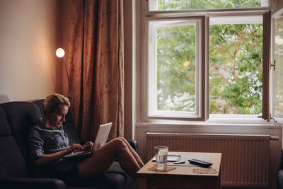 Woman sitting on window at home