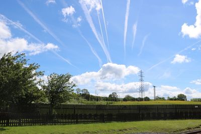 Vapor trails on field against sky