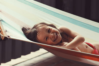 Portrait of happy shirtless boy resting on hammock