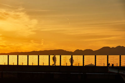 Scenic view of harbor with silhouette people during sunset