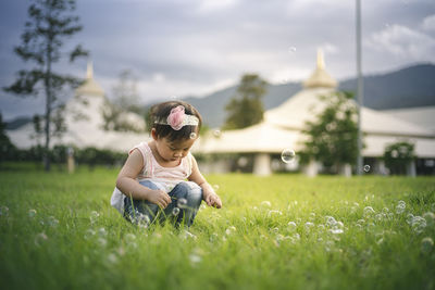 Baby girl crouching on grassy land