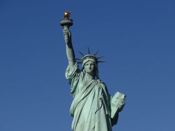 Low angle view of statue of liberty in new york against blue sky