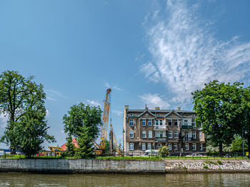 Buildings by river against blue sky