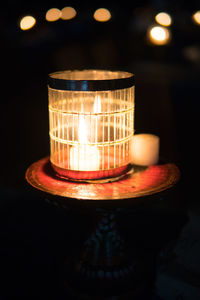 Close-up of illuminated tea light candle in darkroom
