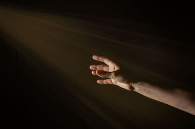 Bright light rays shihing on man's hand in darkness