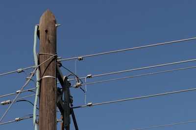 Low angle view of power lines against clear blue sky