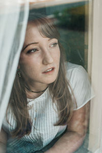 Thoughtful young woman looking through window