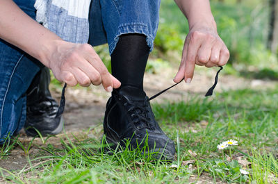 Low section of woman tying shoelaces on grass