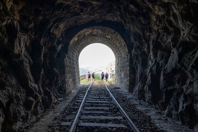 People on railroad tracks in tunnel