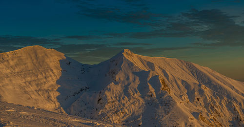 Snow-covered mountain grem at sunset