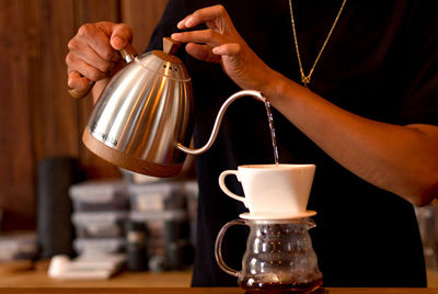 Cropped hands of woman pouring coffee on table