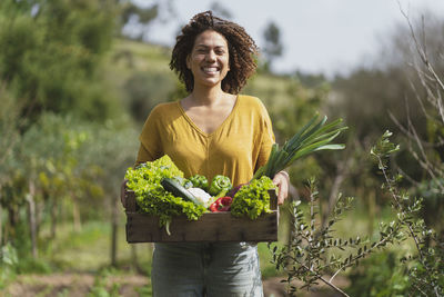 Portrait of smiling young woman standing against plants