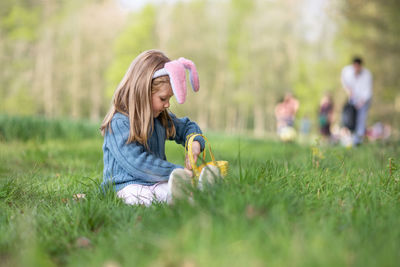 Girl with bunny ears collects the eggs for easter