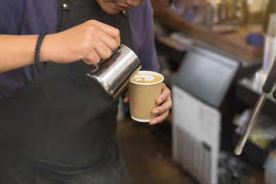 Midsection of man preparing coffee in cafe