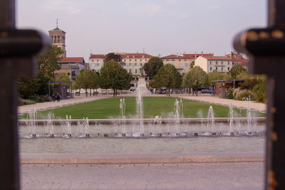 Fountain in city against sky
