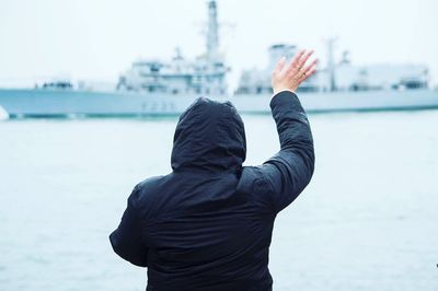 Rear view of person waving at ship