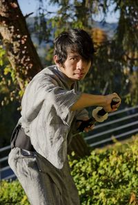 Side view of young man standing against plants