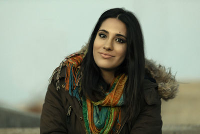 Cute girl with straight hair, coat and scarf smiling at camera