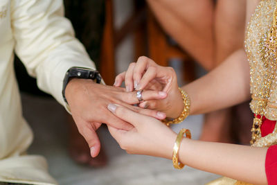 Midsection of wedding couple exchanging finger rings during ceremony