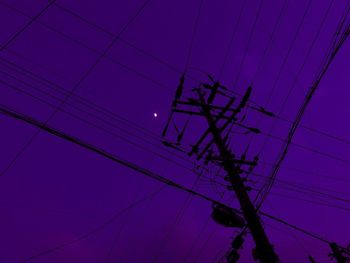 Low angle view of electricity pylon against sky at dusk