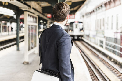 Rear view of man standing at railroad station