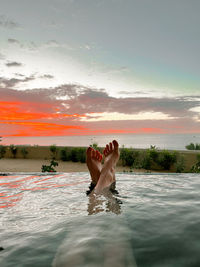 Rear view of woman in sea against sky during sunset
