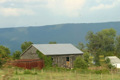 House by trees and mountains against sky