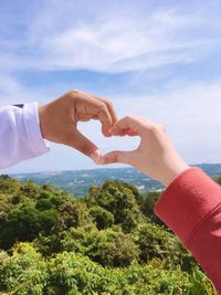 Cropped hand of woman holding hands against sky