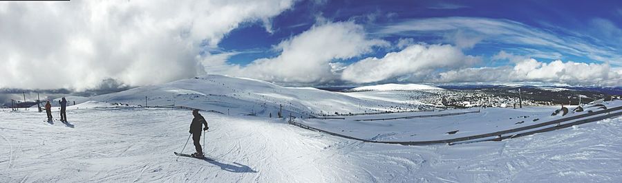 Panoramic view of people skiing against sky
