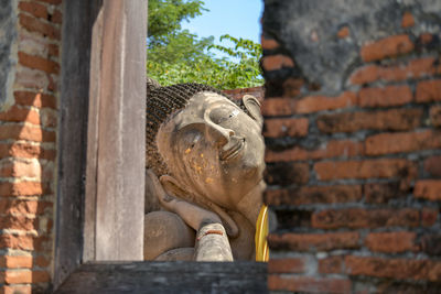 Statue of buddha against brick wall
