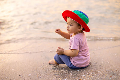 Full length of cute boy sitting on beach