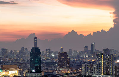 Illuminated cityscape against sky during sunset