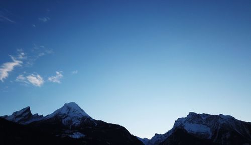 Low angle view of snowcapped mountains against blue sky