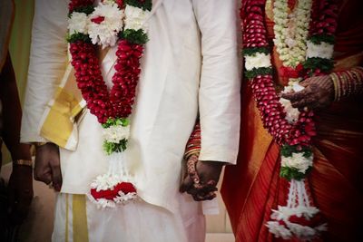 Midsection of bride and bridegroom holding hands during wedding ceremony