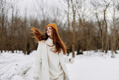 Portrait of young woman standing against trees during winter