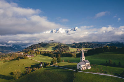 Aerial view at church on mount buchberg with snow covered mountains in the background, austria.