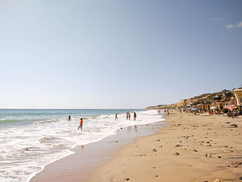 People at beach against clear sky