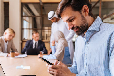 Side view of businessman using mobile phone while standing in office