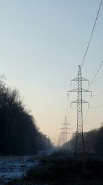 Low angle view of electricity pylon against sky during sunset