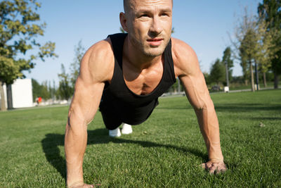 Portrait of young man exercising on field