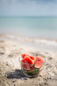 Transparent bowl with watermelon lobes on the beach. sky and sea.