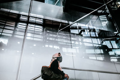 Low angle view of woman wearing mask standing against building